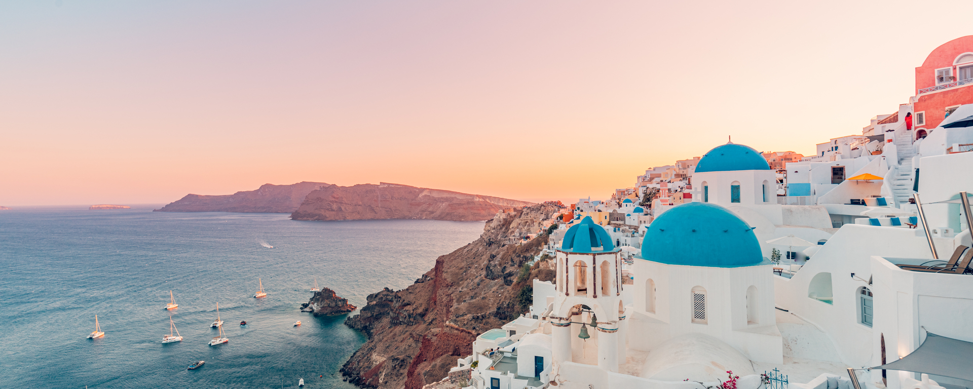 Whitewashed cliffside village above the blue Aegean Sea at golden hour
